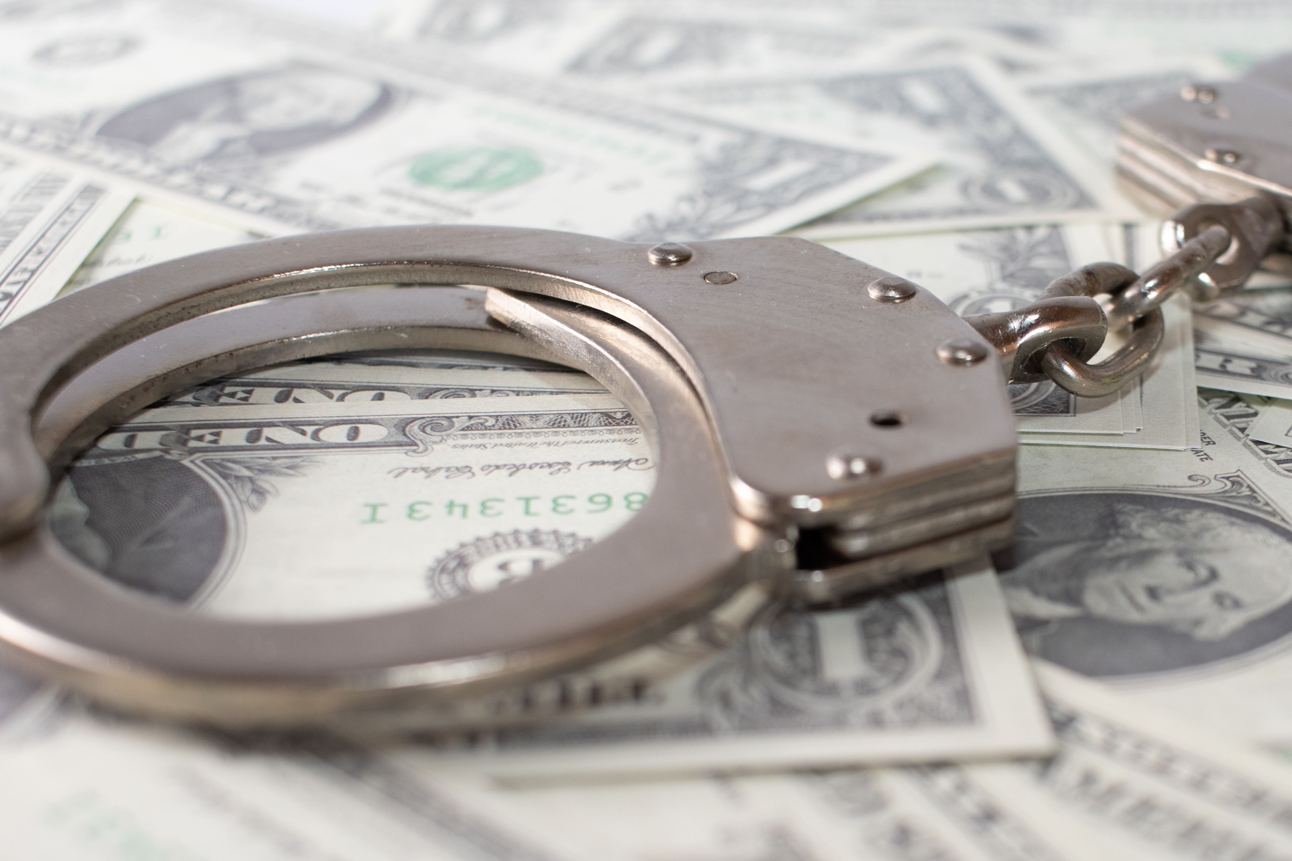 closeup-view-metal-handcuffs-dollars