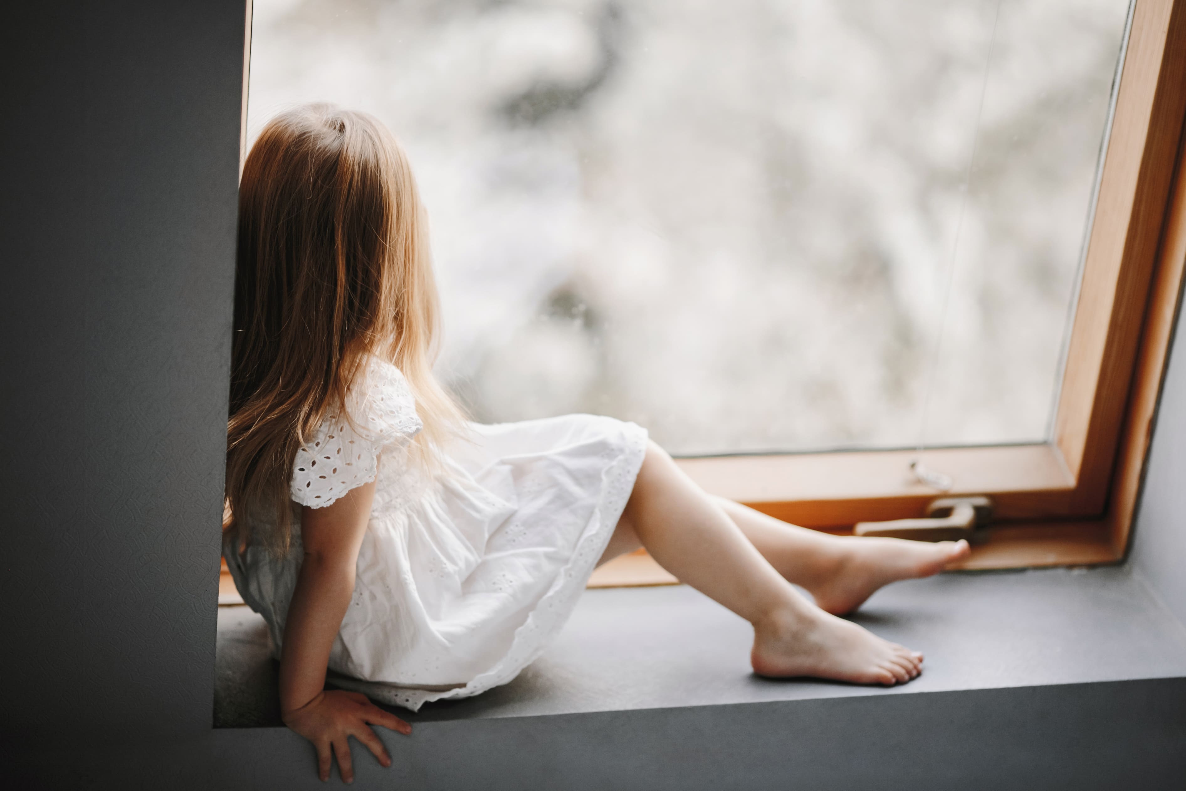 little-child-tender-white-dress-is-sitting-windowsill