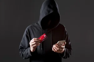 front-view-male-hacker-holding-smartphone-credit-card (1)